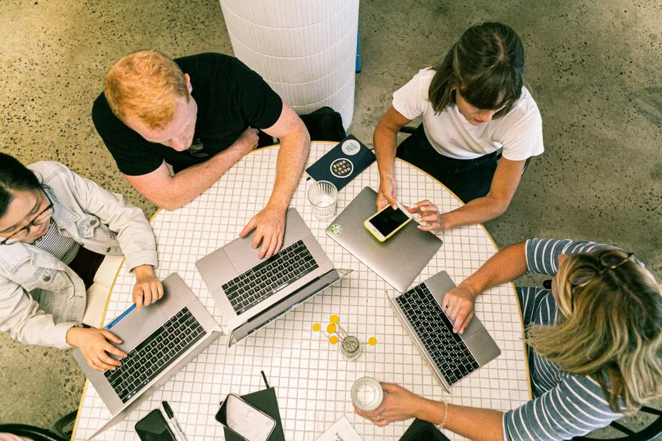 Gros plan sur des mains en train de taper sur un ordinateur portable posé sur un bureau de bureau, évoquant le travail ou la communication en ligne.